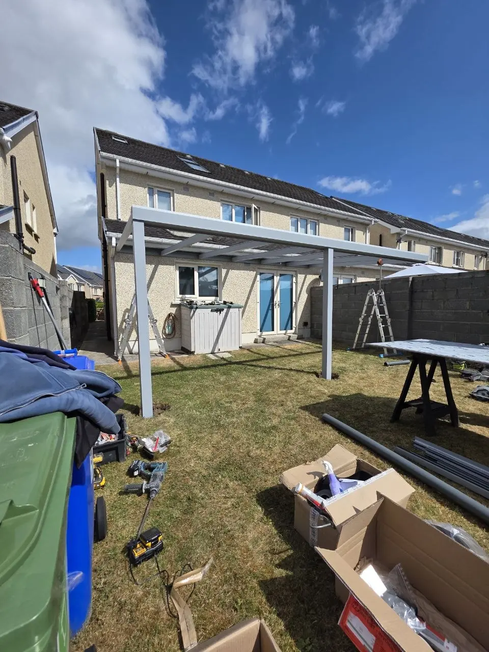 Silver-grey aluminium pergola frame during installation on the lawn