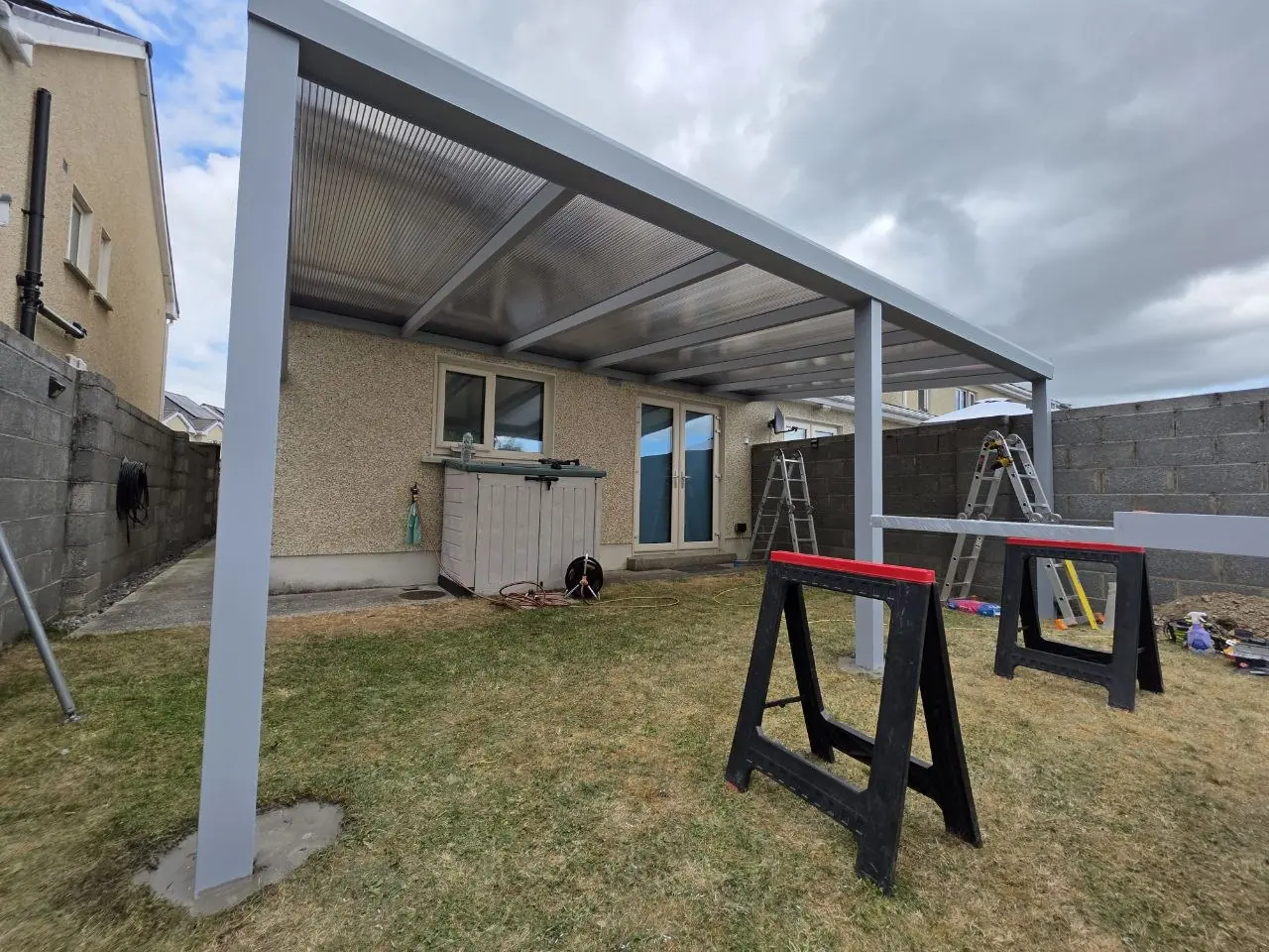 Three-post wall-mounted pergola taking shape over the rear garden