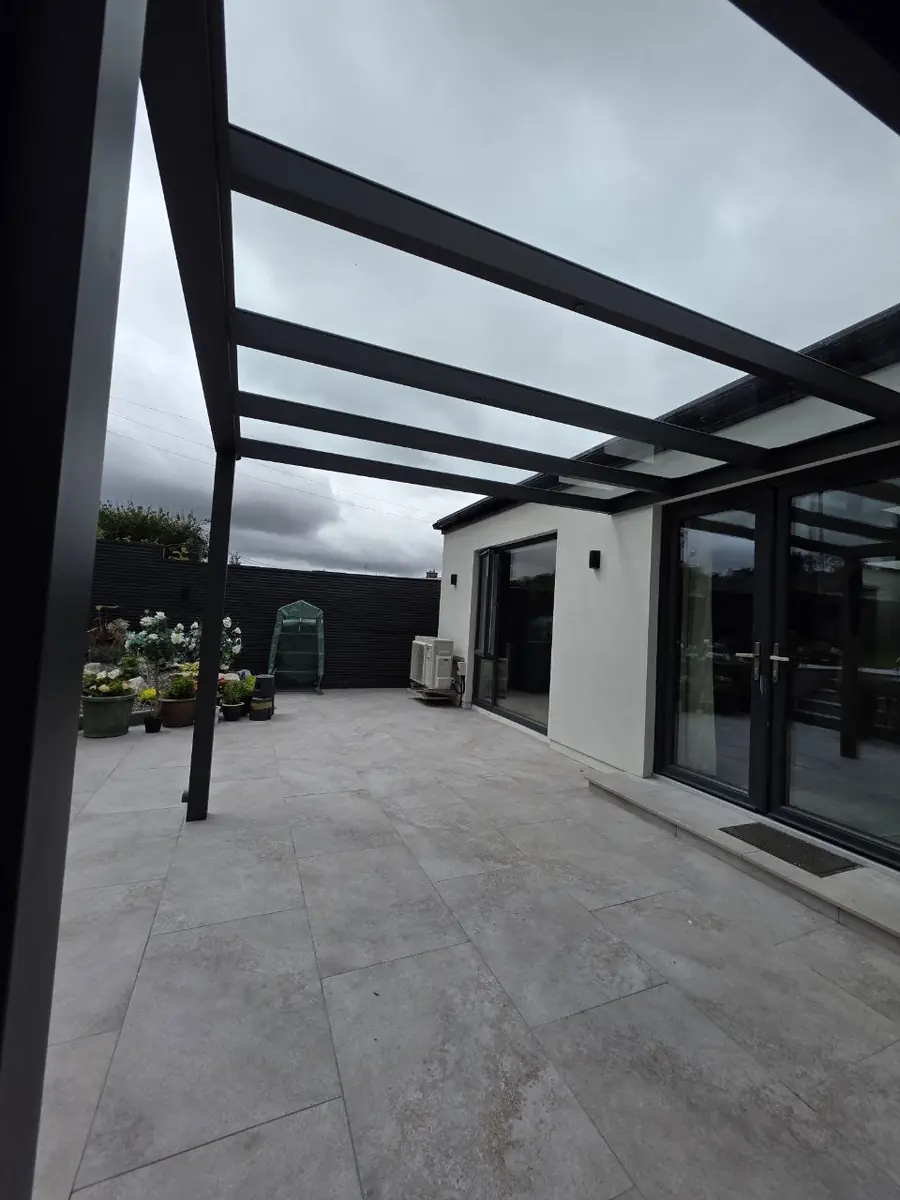 Completed wall-mounted aluminium pergola with a clear laminated safety glass roof in Middletown, Co. Cork