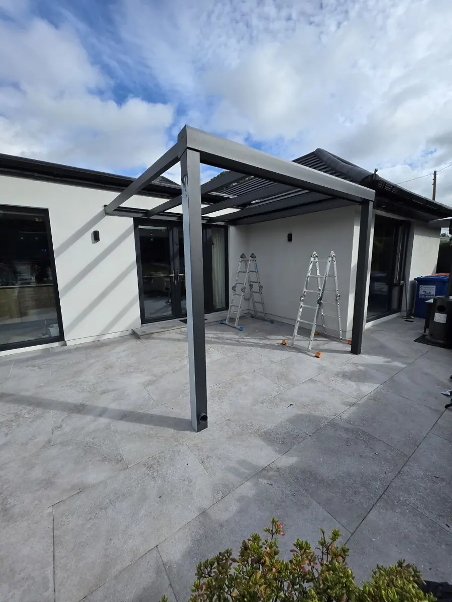 Anthracite aluminium pergola frame during installation on the tiled terrace