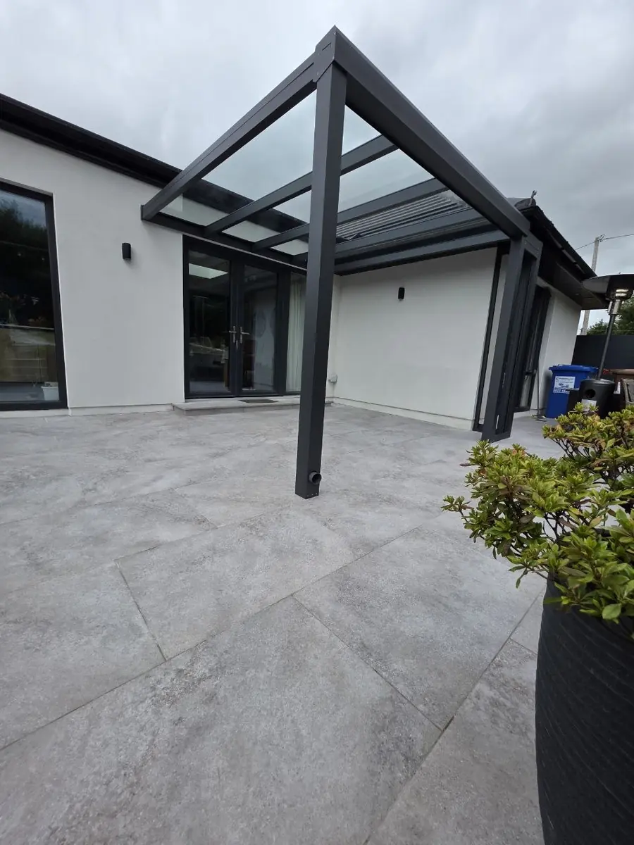 Front corner view of the completed wall-mounted glass-roof pergola
