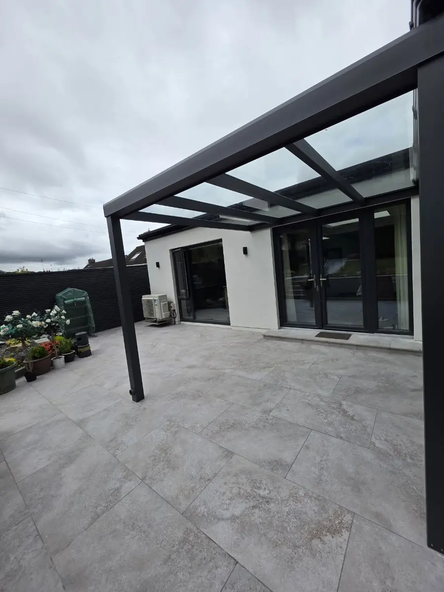 Wall-mounted glass pergola protecting the rear entrance and tiled terrace