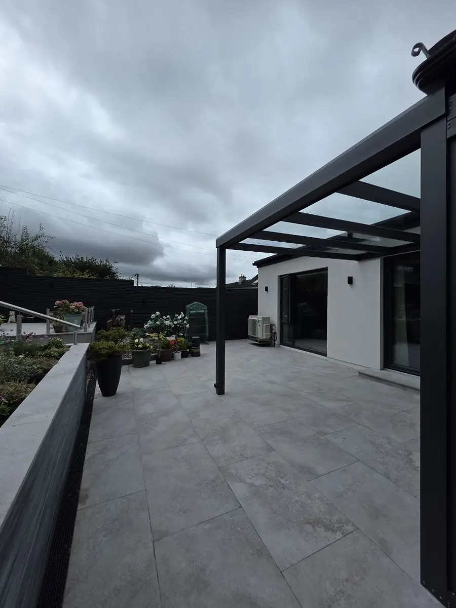 Covered rear terrace beneath the wall-mounted glass pergola in Middletown