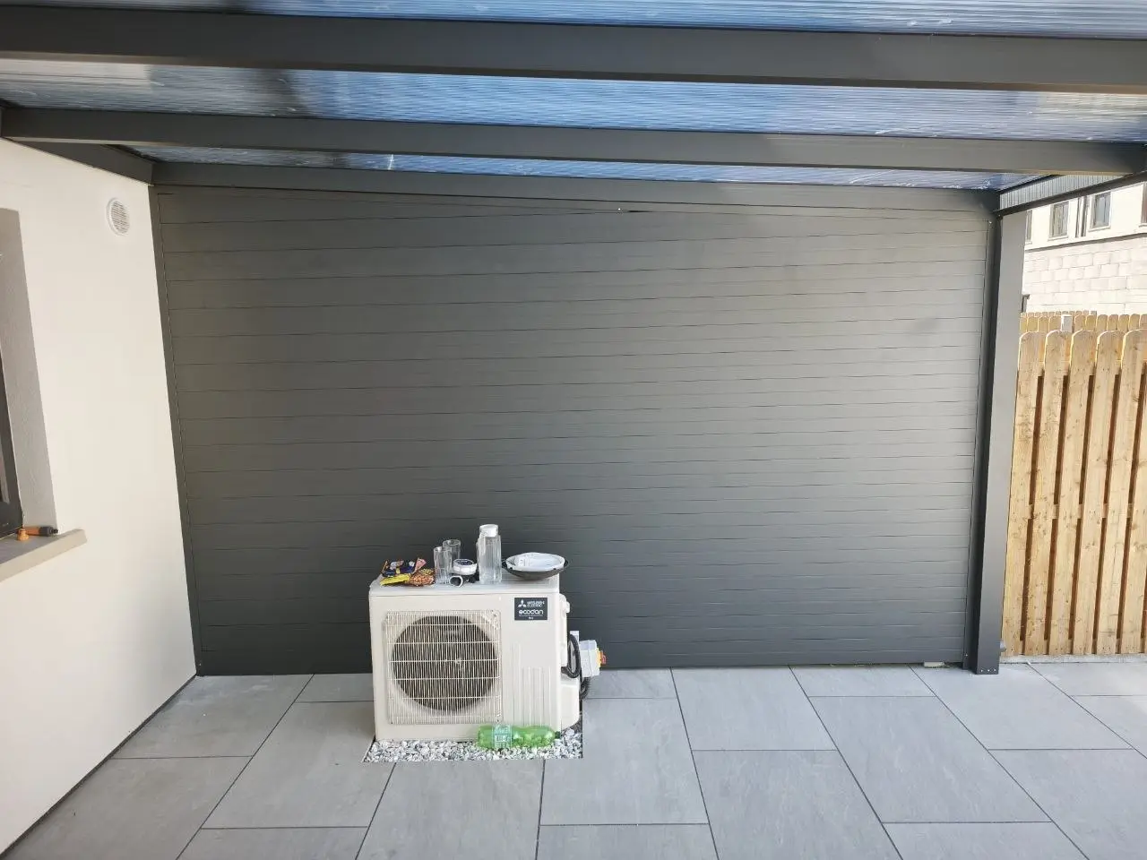 Solid anthracite privacy wall beneath the polycarbonate pergola