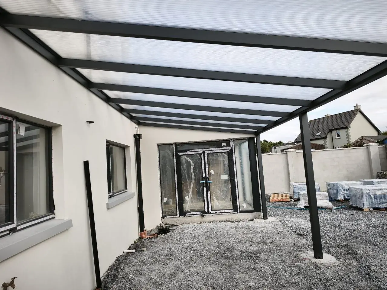 Covered rear terrace beneath a fixed polycarbonate pergola in Ennis