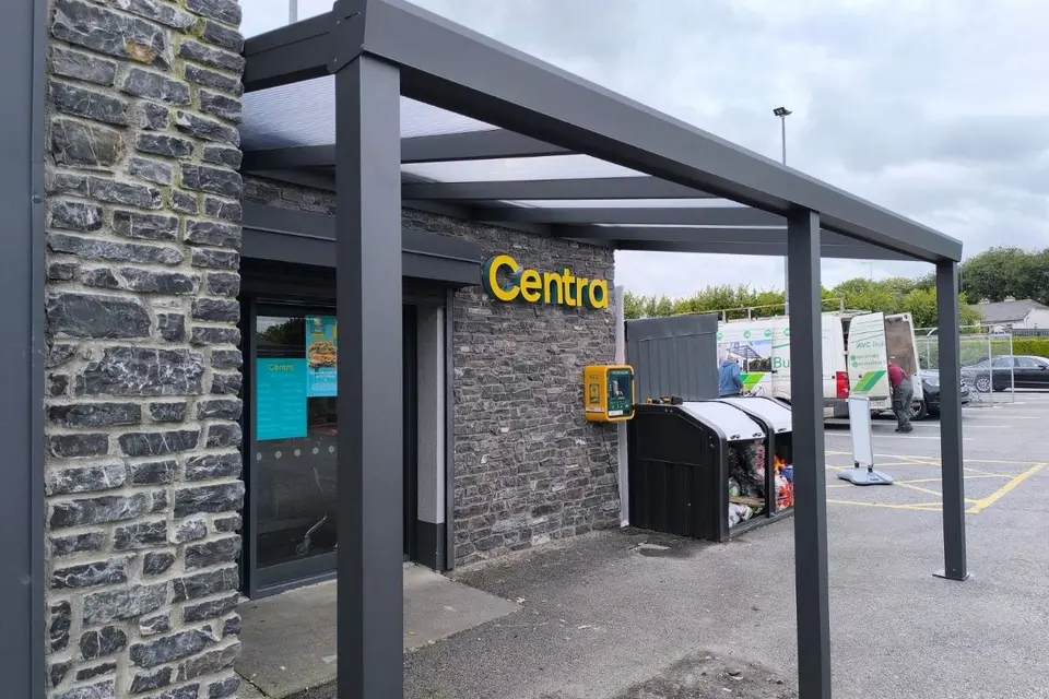 Black aluminium entrance canopy with a clear polycarbonate roof at a Centra store in County Roscommon