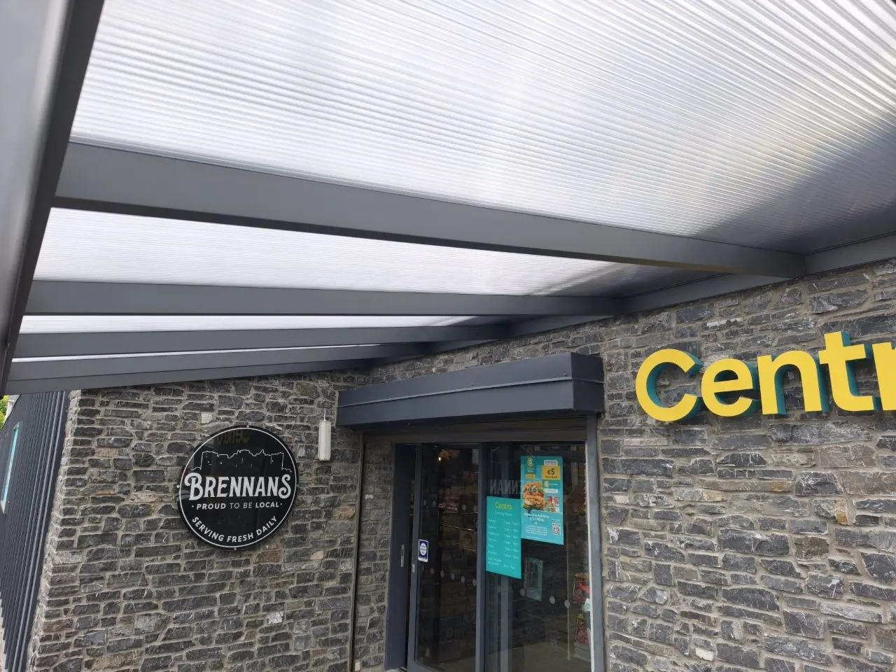 Clear polycarbonate roof and black aluminium rafters above the store entrance