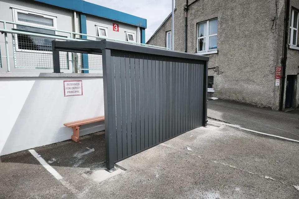 Black aluminium school shelter with a clear polycarbonate roof and privacy wall in Cashel, County Tipperary
