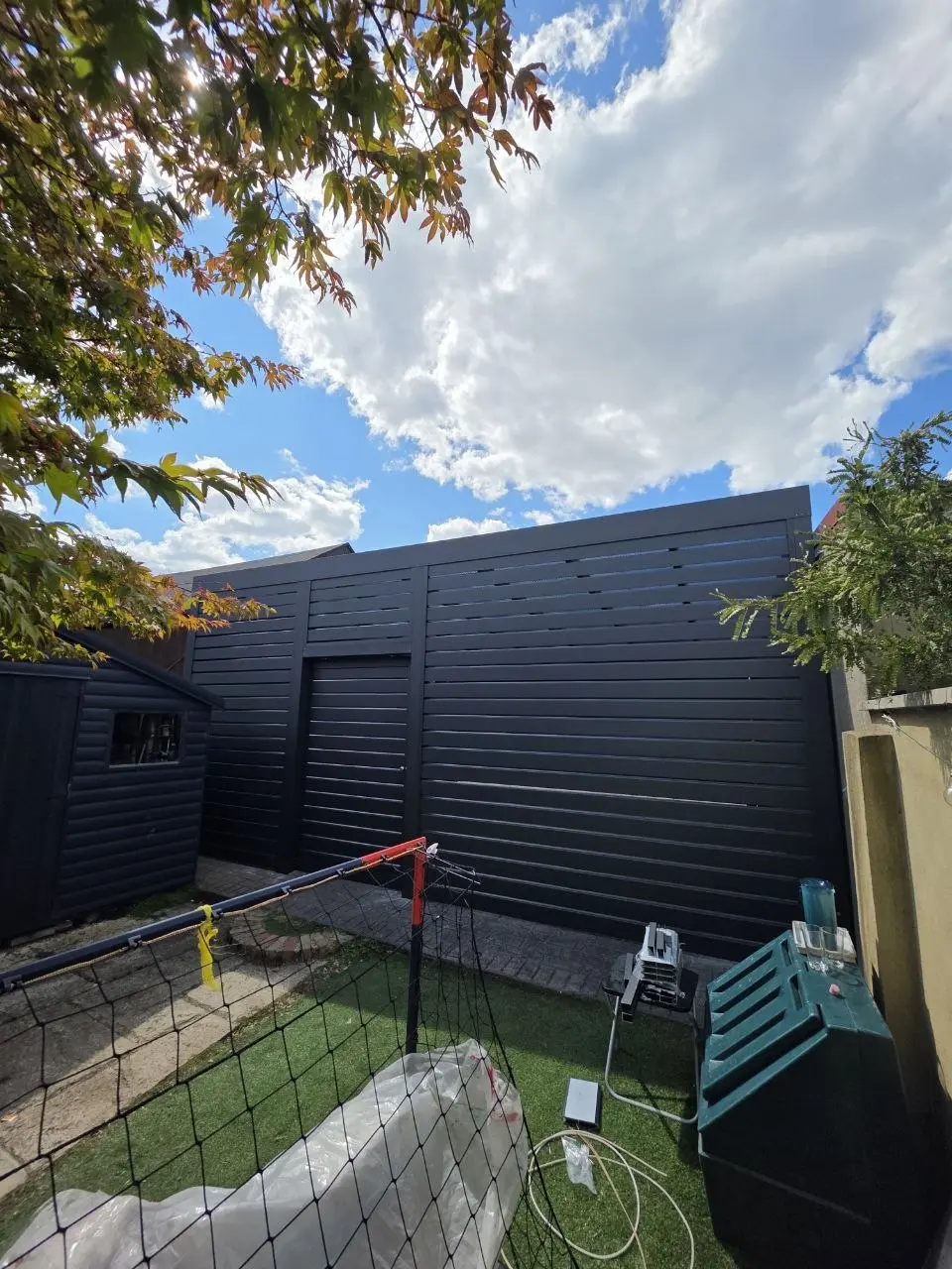 Garden-facing exterior of the enclosed aluminium carport garage in Monkstown
