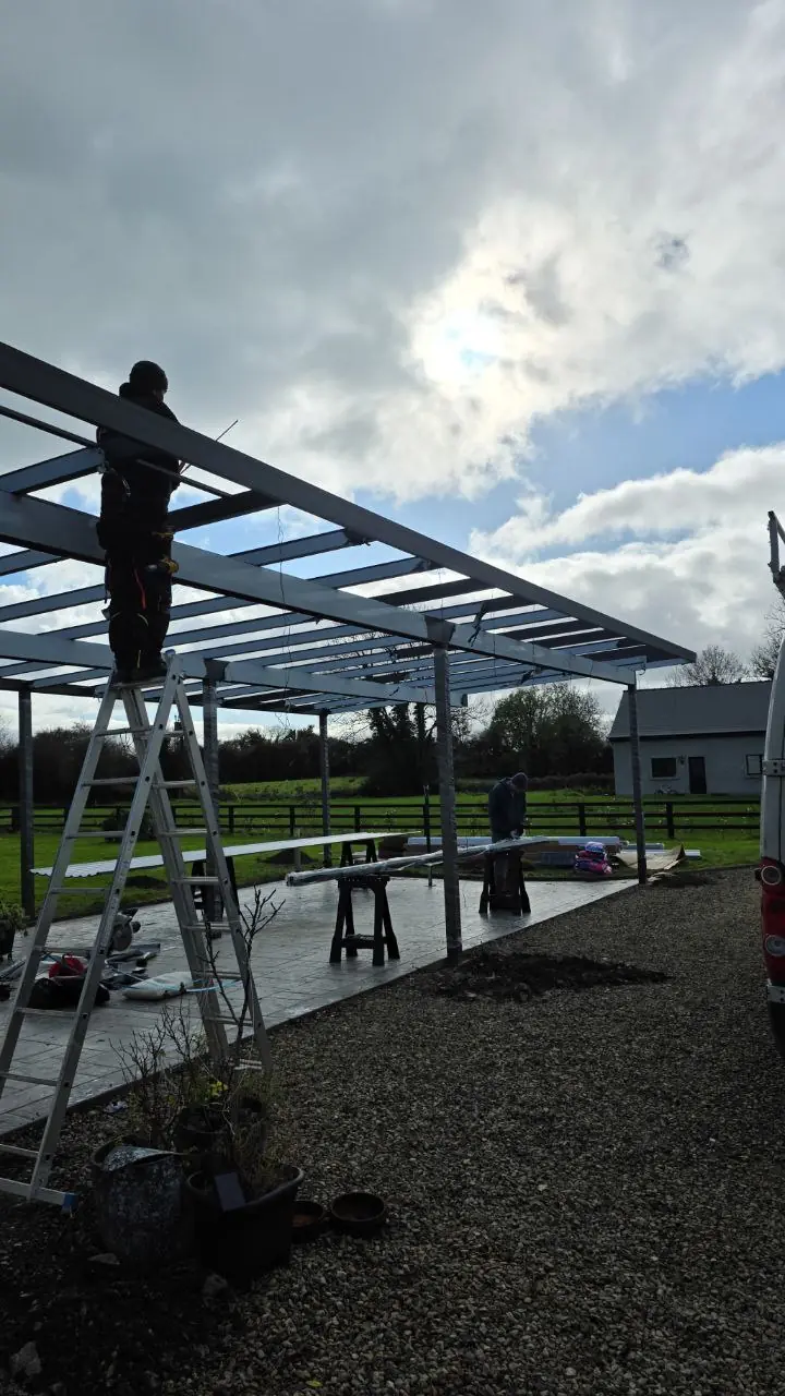 Installers preparing the roof frame of the four-car aluminium carport