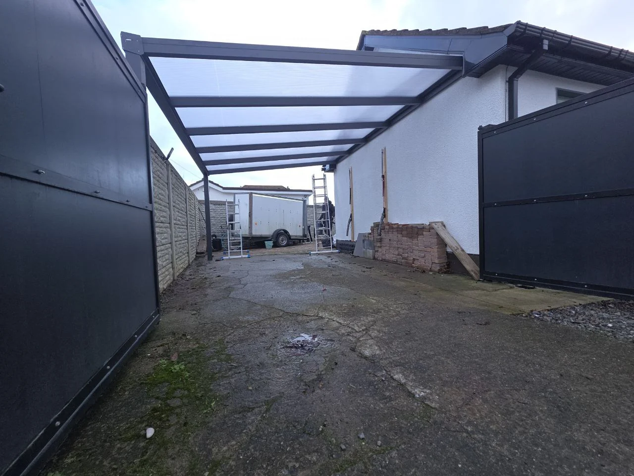 Completed front view of the large wall-mounted polycarbonate carport beside a Dublin home