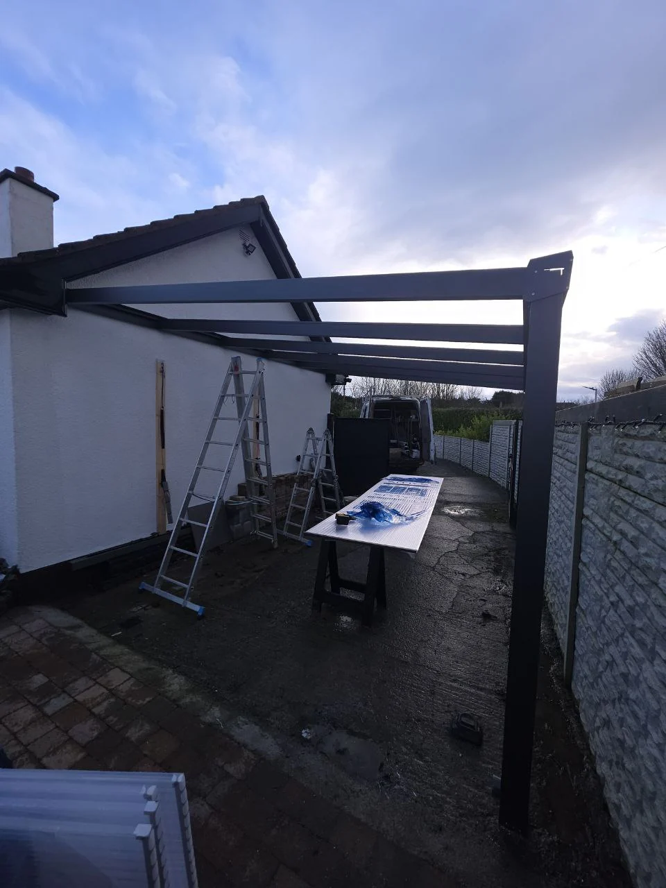 Wide view of the large wall-mounted aluminium carport frame during installation