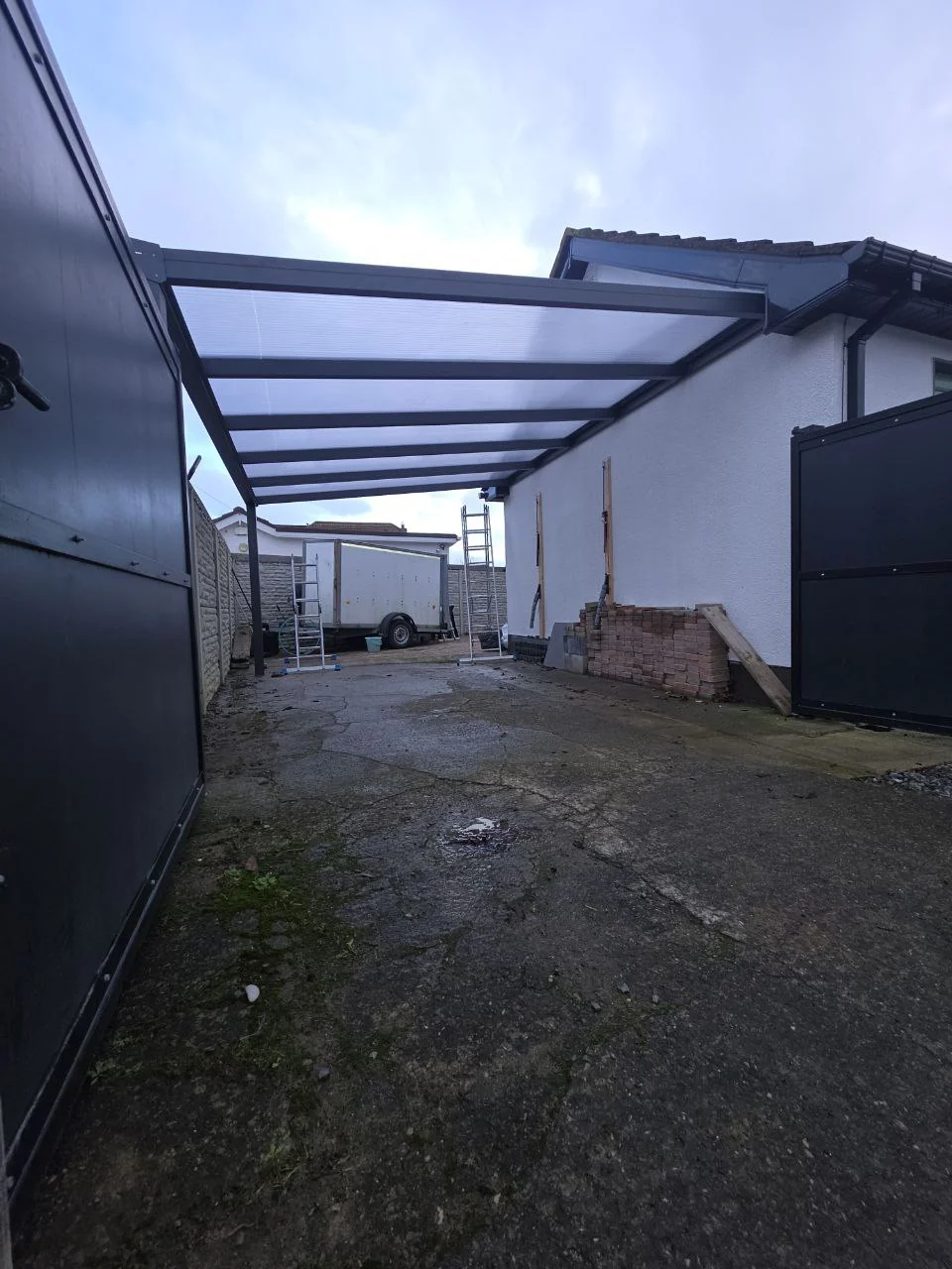 Large wall-mounted aluminium carport with transparent polycarbonate roof completed in Dublin