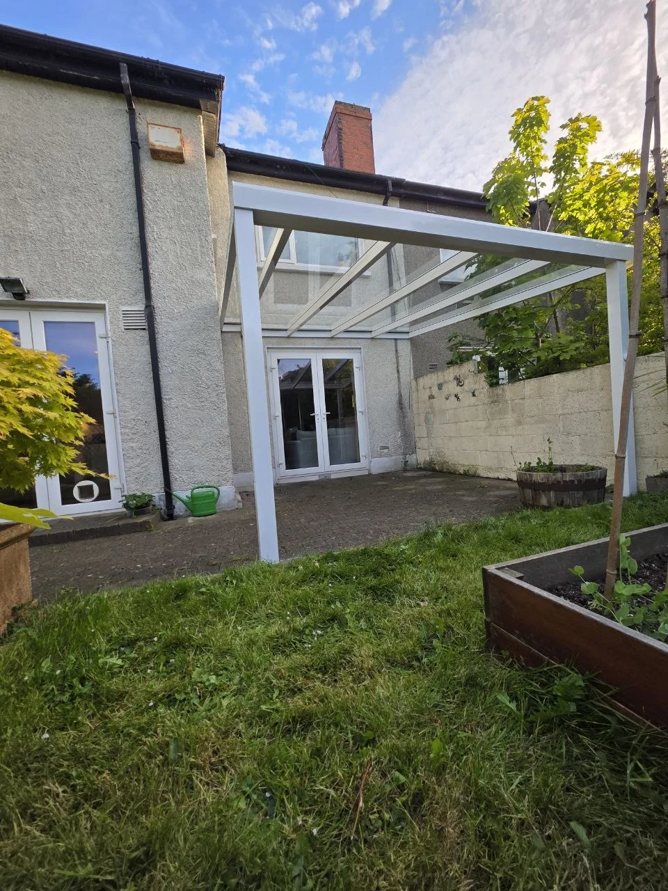 White wall-mounted glass pergola installed beside the rear door of a residential property in Dublin
