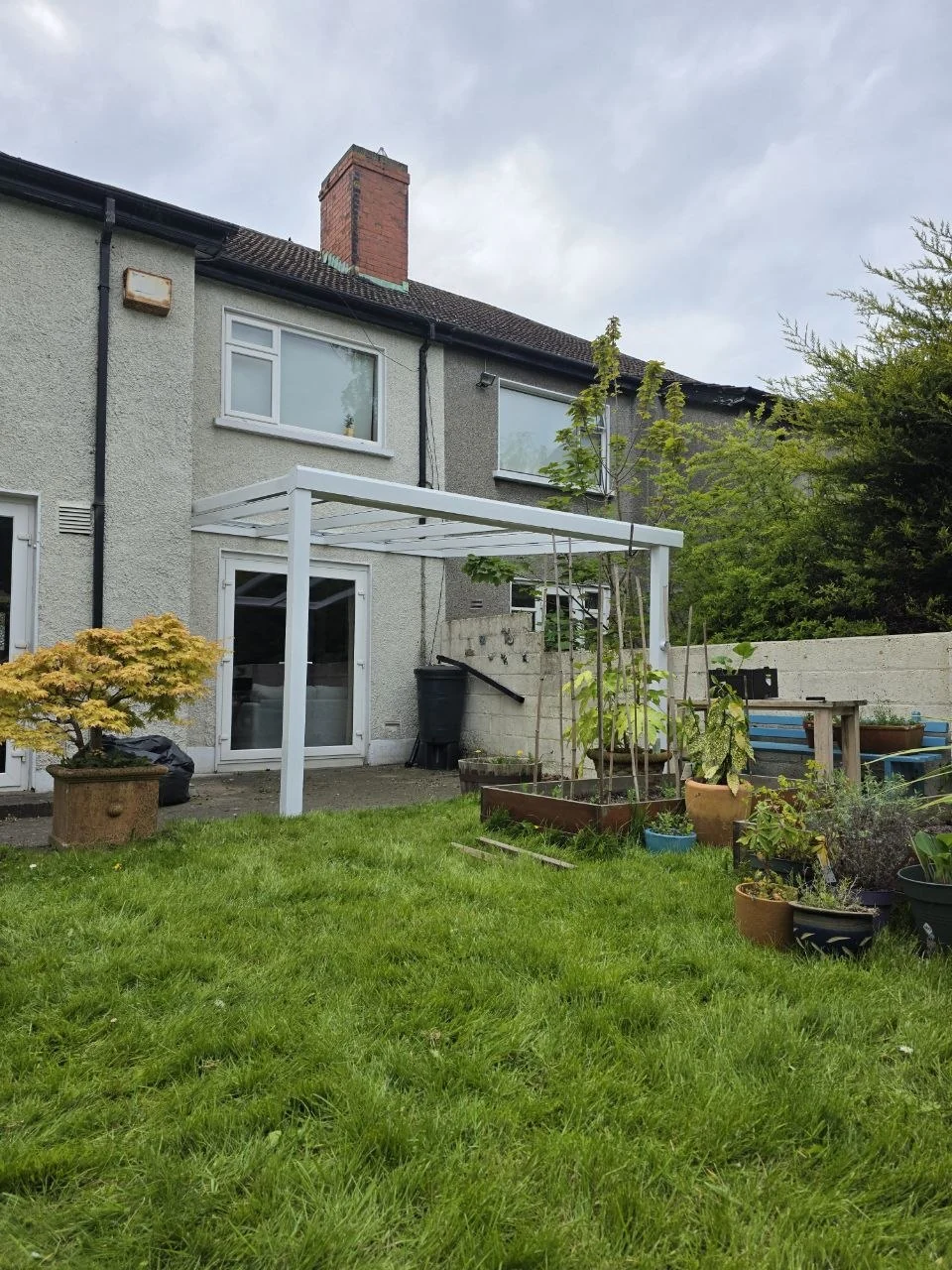 Wide garden view of the completed white glass pergola at a Dublin home
