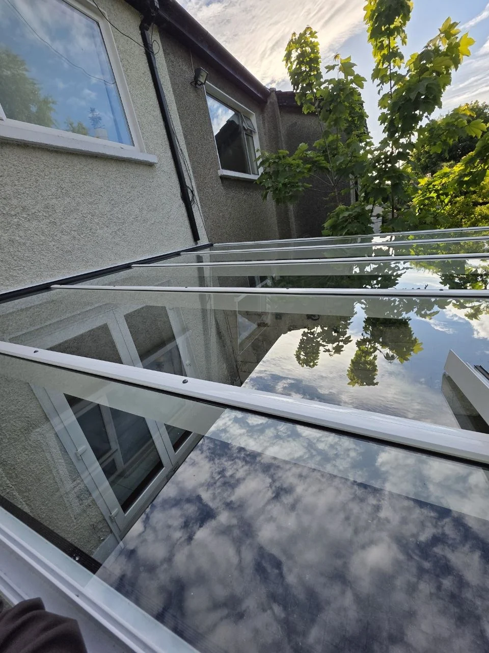 Close view of the glass roof panels and white aluminium pergola frame