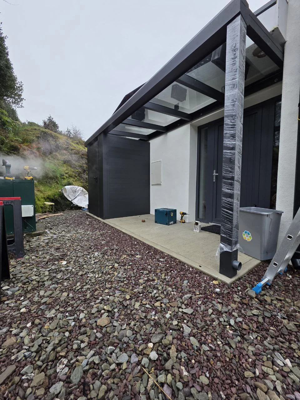 Completed wall-mounted glass entrance canopy with integrated storage room in Cork