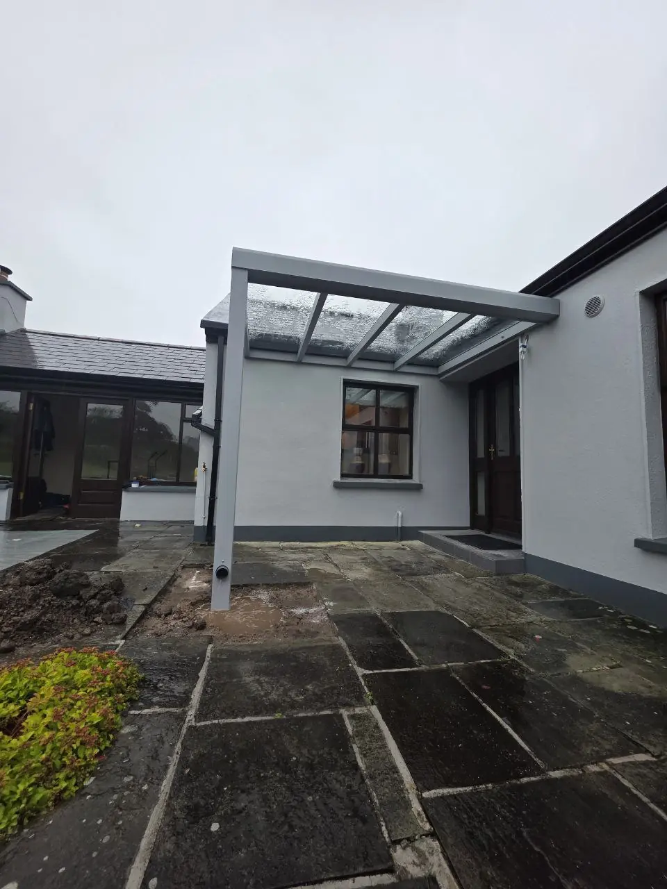 Angled view of a grey aluminium canopy with a polycarbonate roof at the Westport home