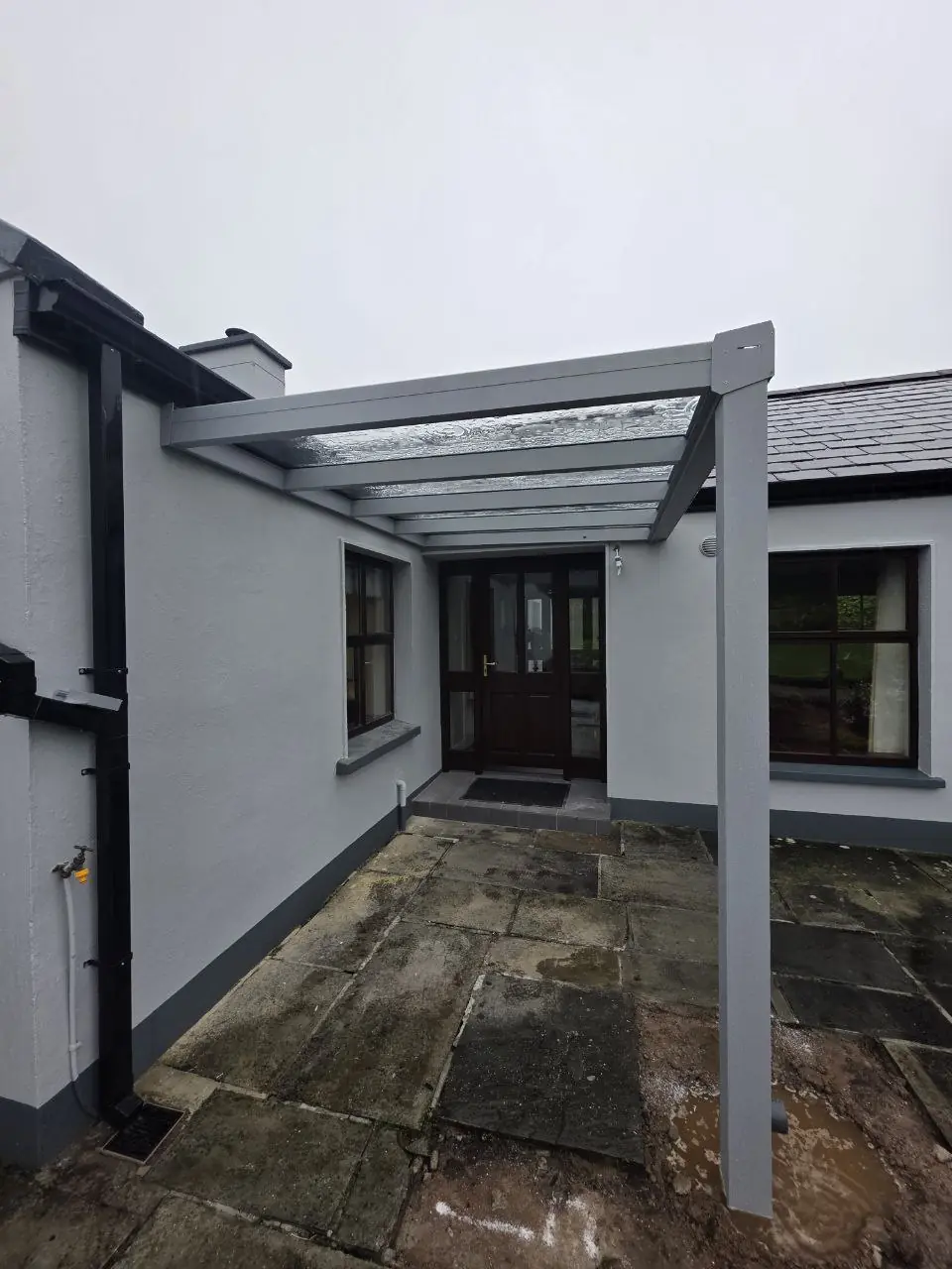Grey wall-mounted polycarbonate canopy protecting an entrance at a residential property in Westport