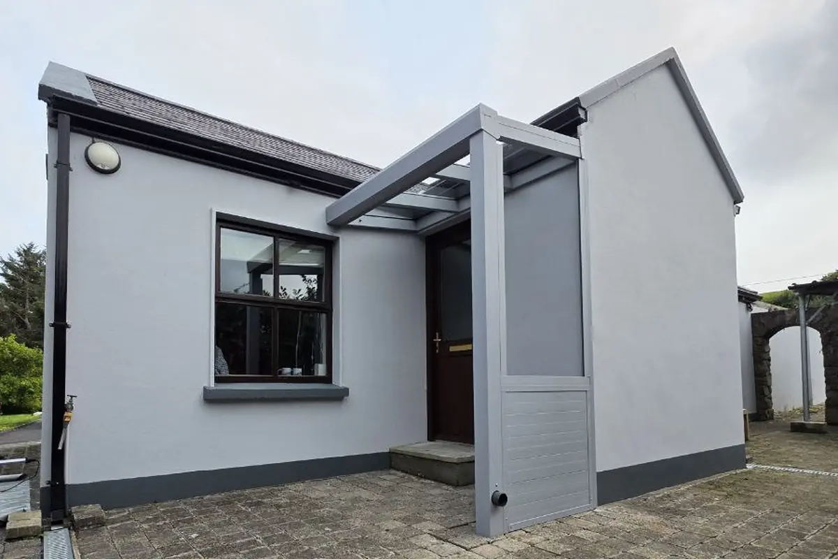 Completed grey wall-mounted entrance canopy with a polycarbonate roof and partial side wall in Westport