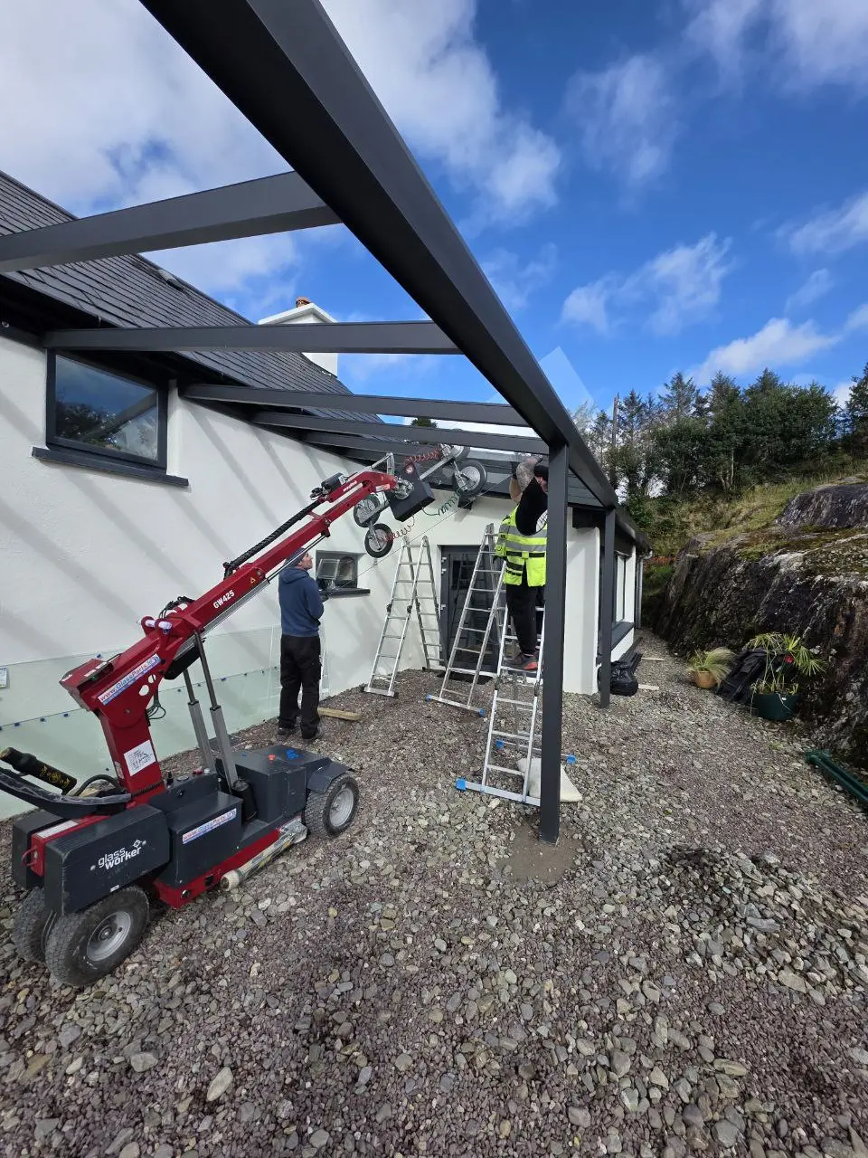 Specialist lifting equipment positioning a large glass roof panel in Bantry