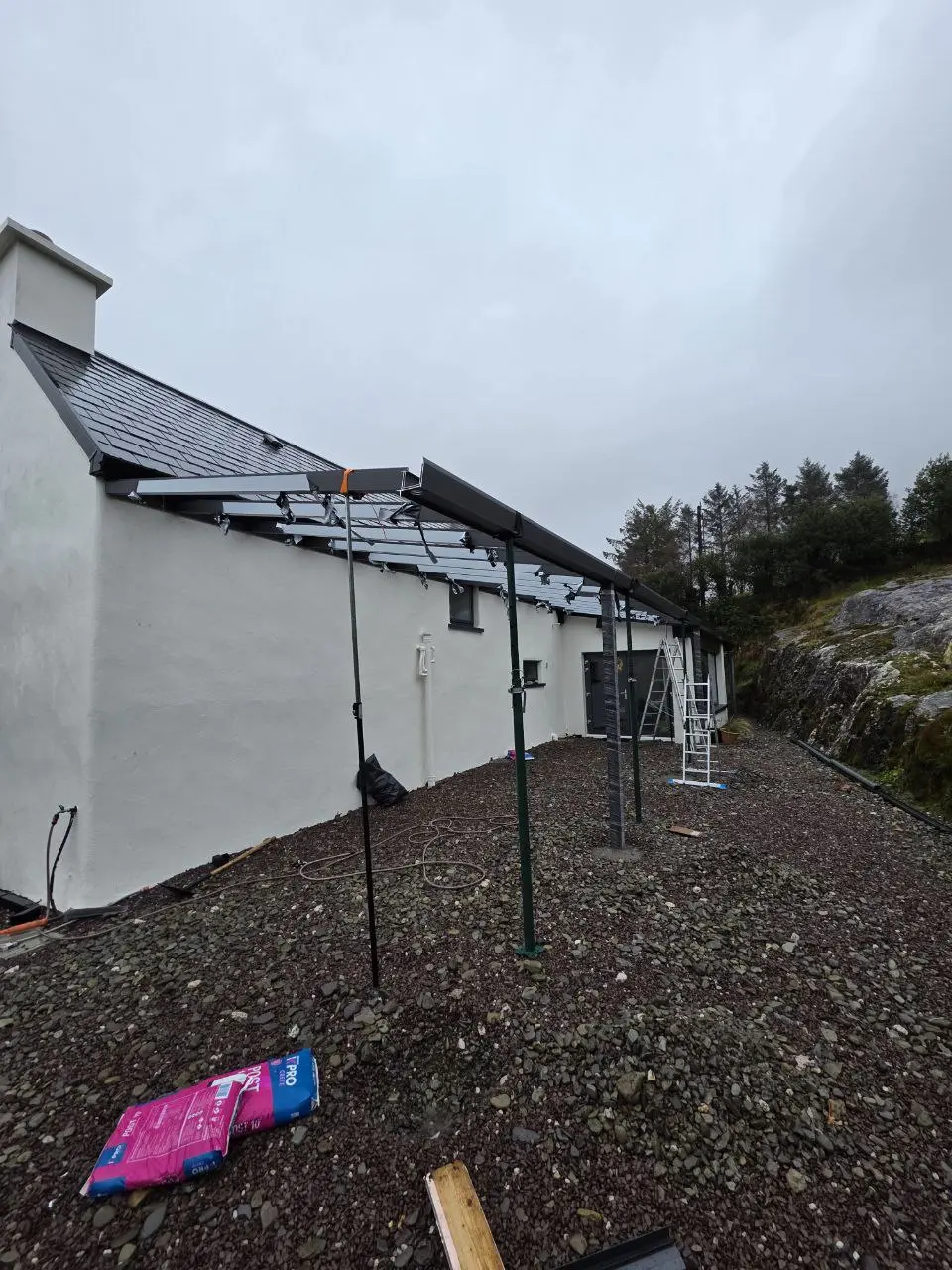 Large glass panels being installed on the wall-mounted pergola in Bantry