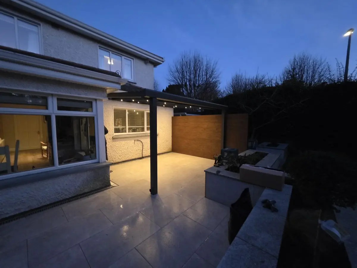 Wide evening view of the wall-mounted pergola with integrated lighting