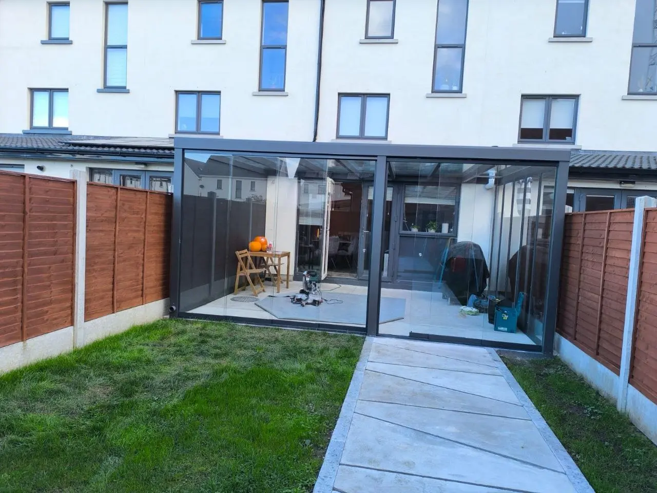 Wide garden view of the completed black aluminium and glass pergola in Dublin