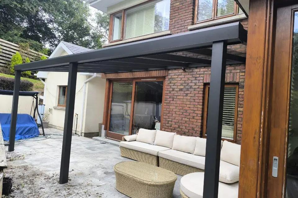 Wall-mounted glass pergola installed on a timber-clad home in Wexford