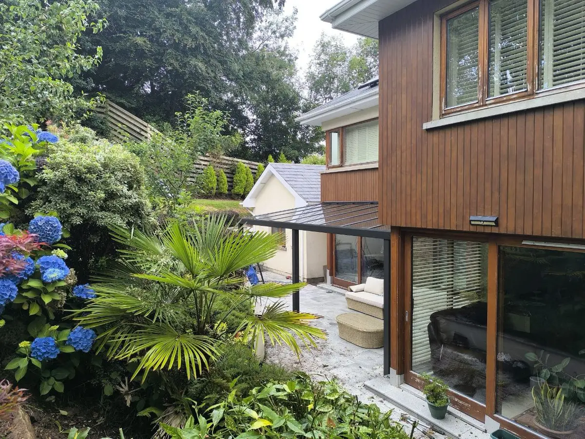 Side garden view of the black aluminium pergola attached to the house