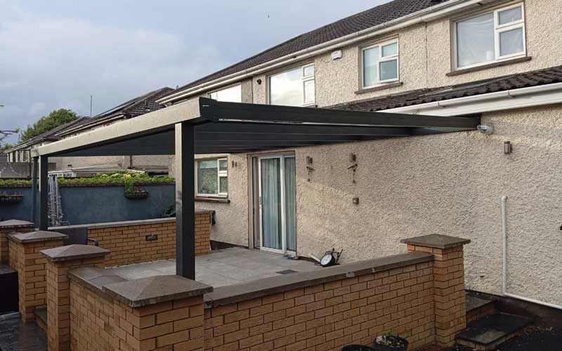 Wall-mounted aluminium pergola with glass roof at a residential home