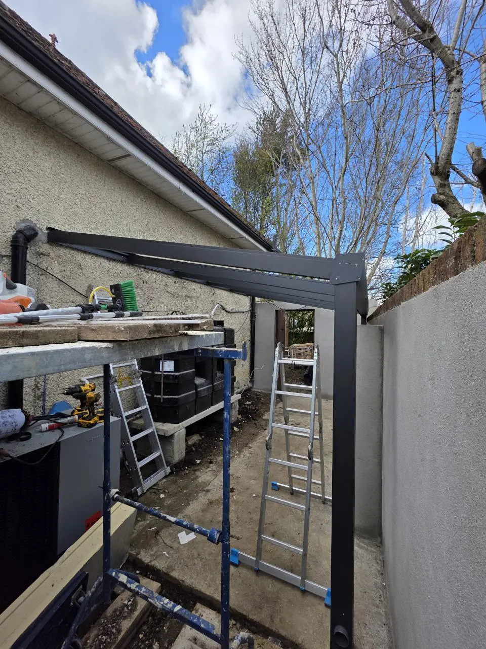 Black aluminium canopy frame during installation beside a Dublin home