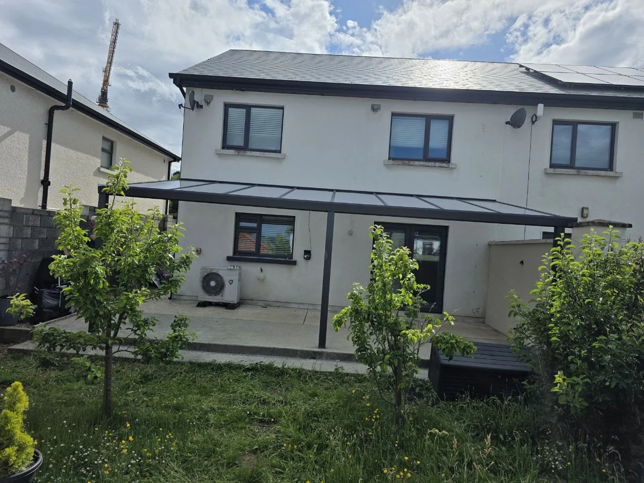 Long wall-mounted polycarbonate pergola covering a rear patio in Rathdrum, County Wicklow