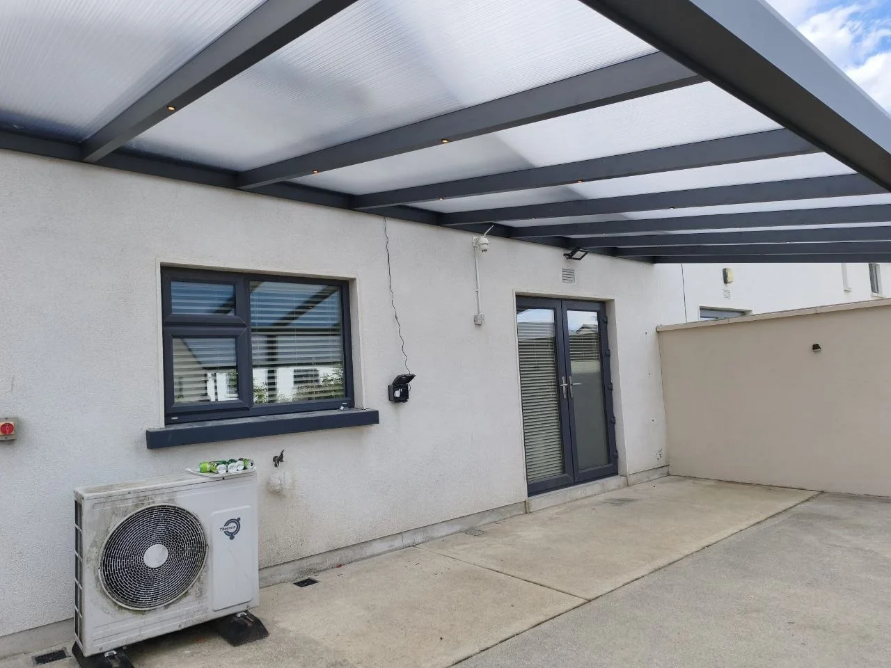 Covered concrete patio beneath the long wall-mounted pergola in Rathdrum