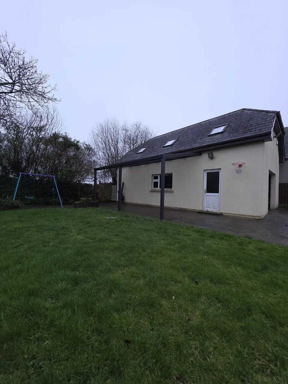 Wide garden view of the completed wall-mounted pergola in Ballymacoonogue
