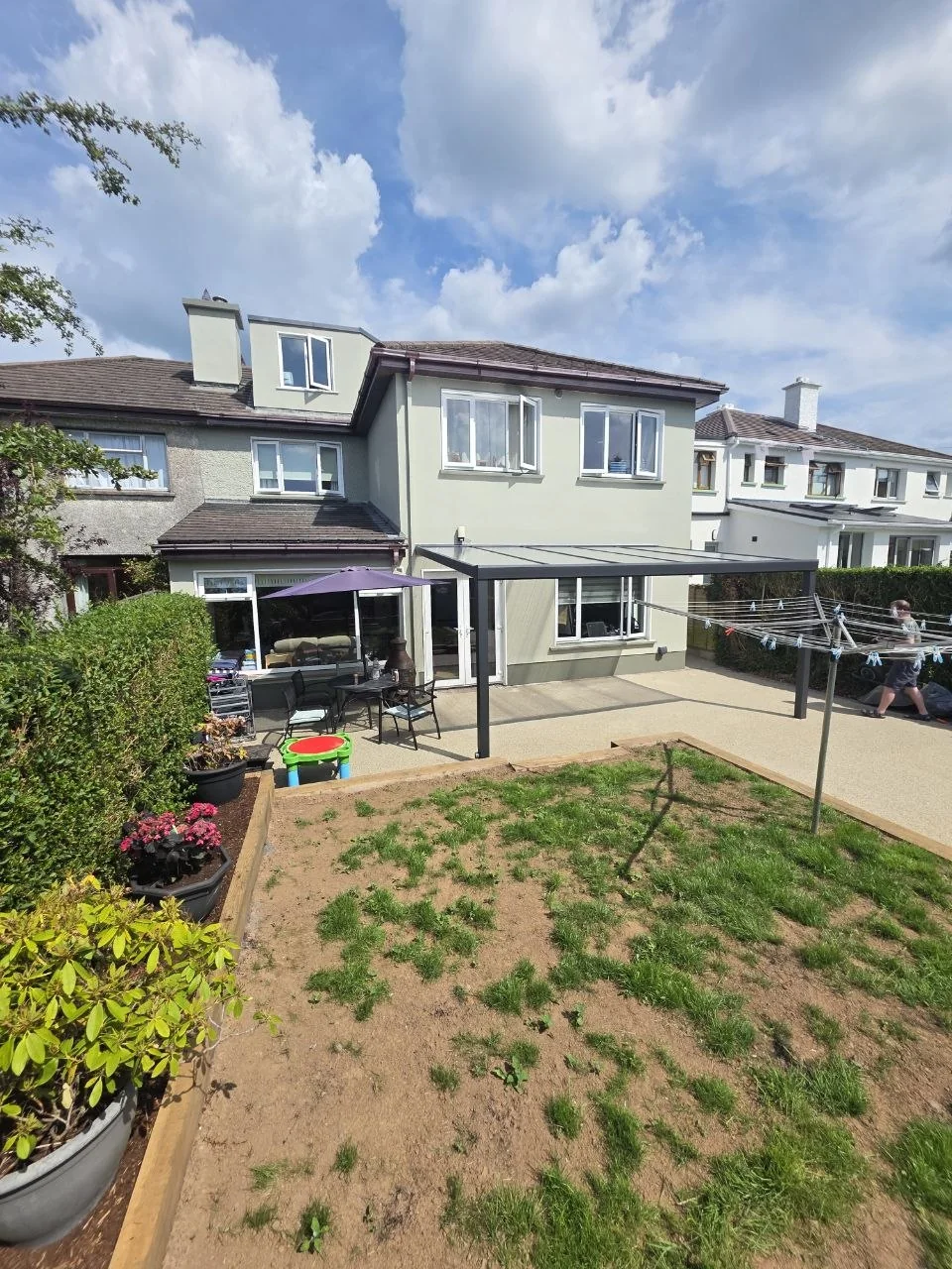 Garden view of the completed wall-mounted pergola covering the rear patio in Galway