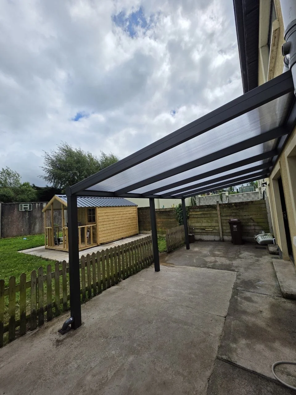 Side view of the open-sided polycarbonate pergola covering the rear patio in Newport