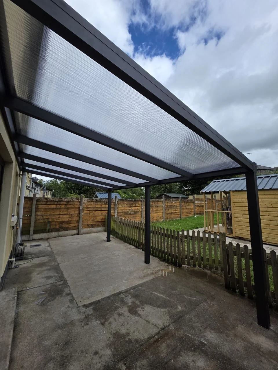 View beneath the transparent polycarbonate roof of the residential pergola in Newport