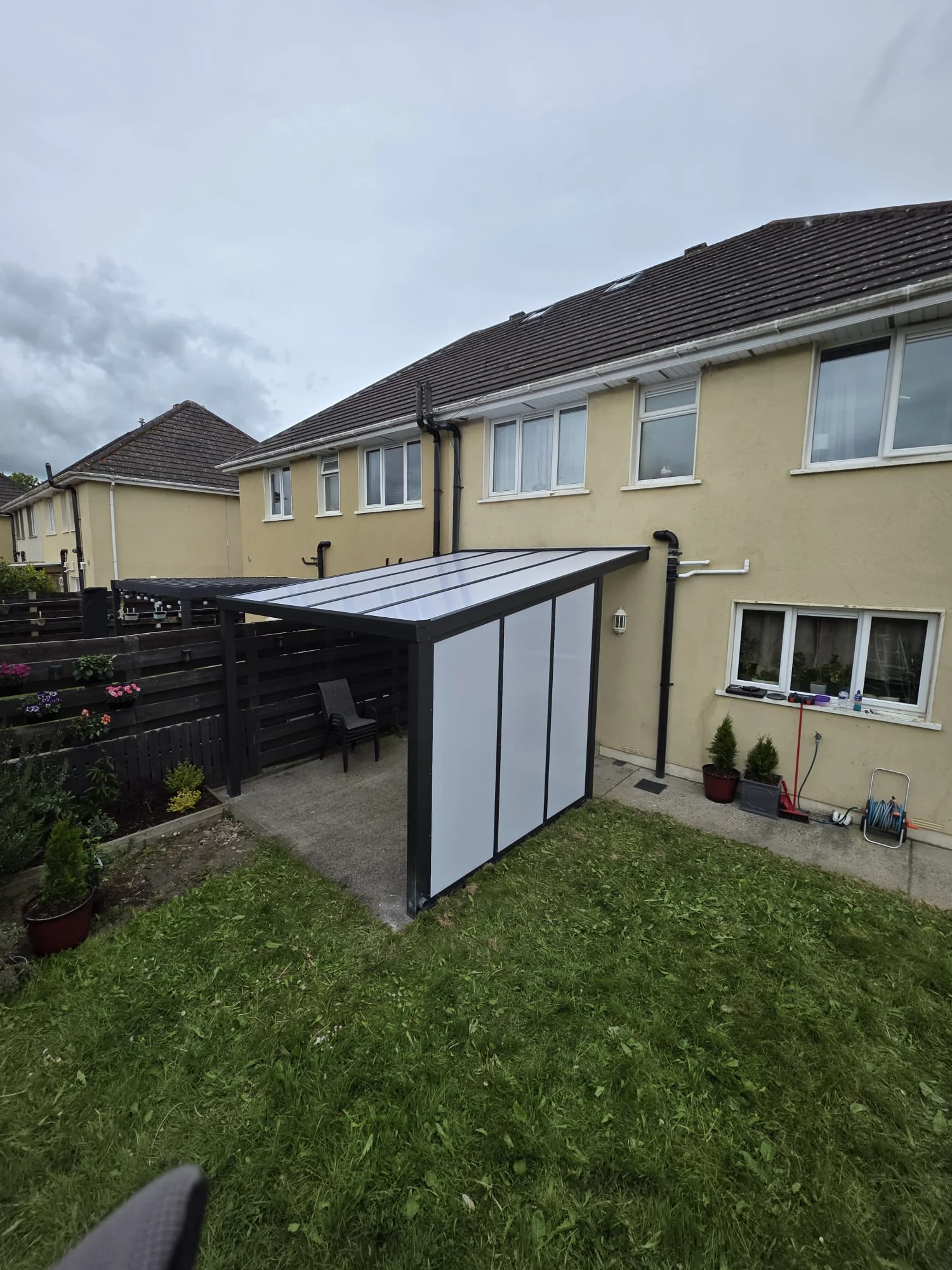 Completed wall-mounted opal polycarbonate pergola with matching side wall in Portlaoise, County Laois