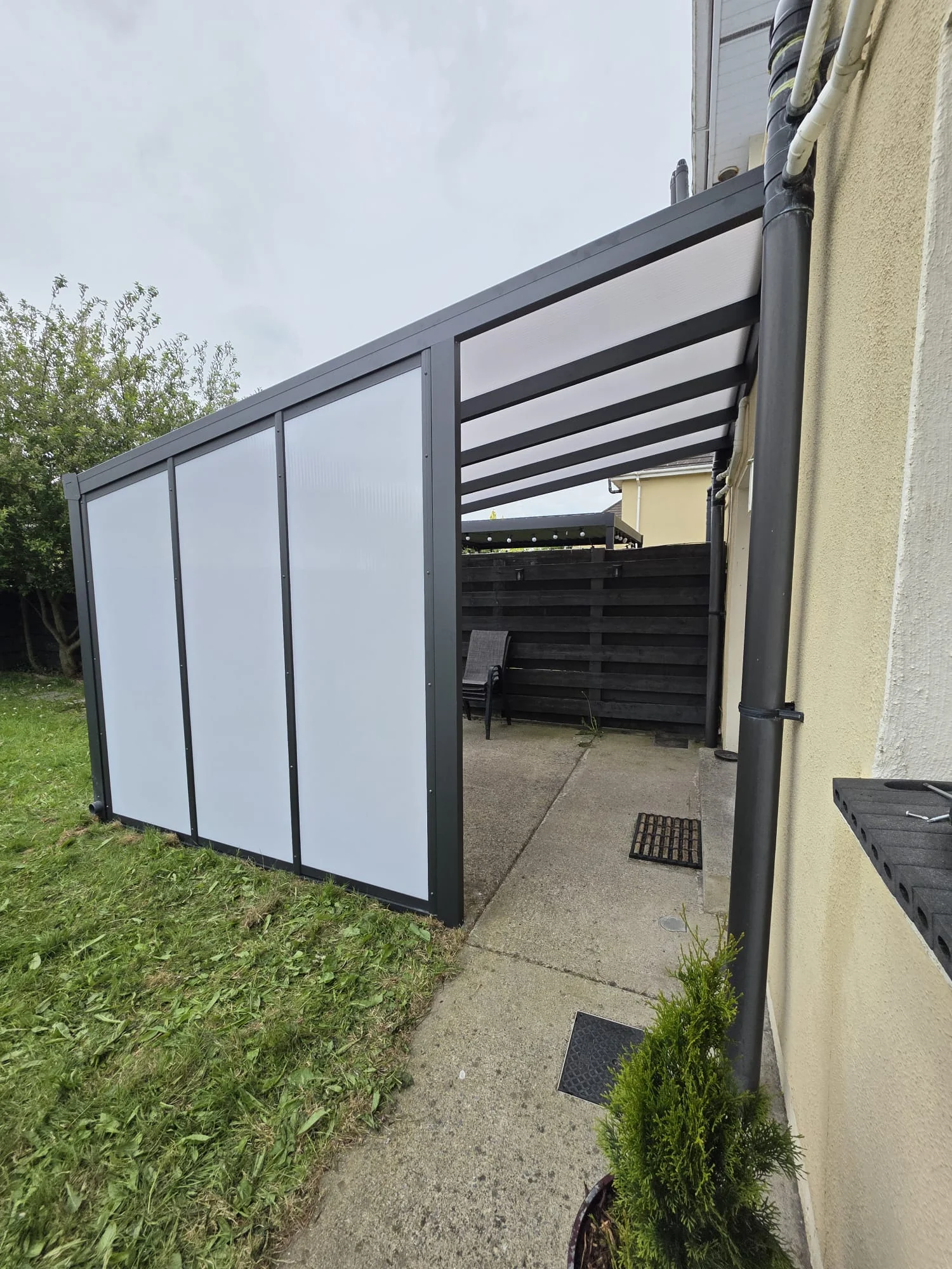 Matching opal polycarbonate side wall providing additional shelter beside the Portlaoise pergola