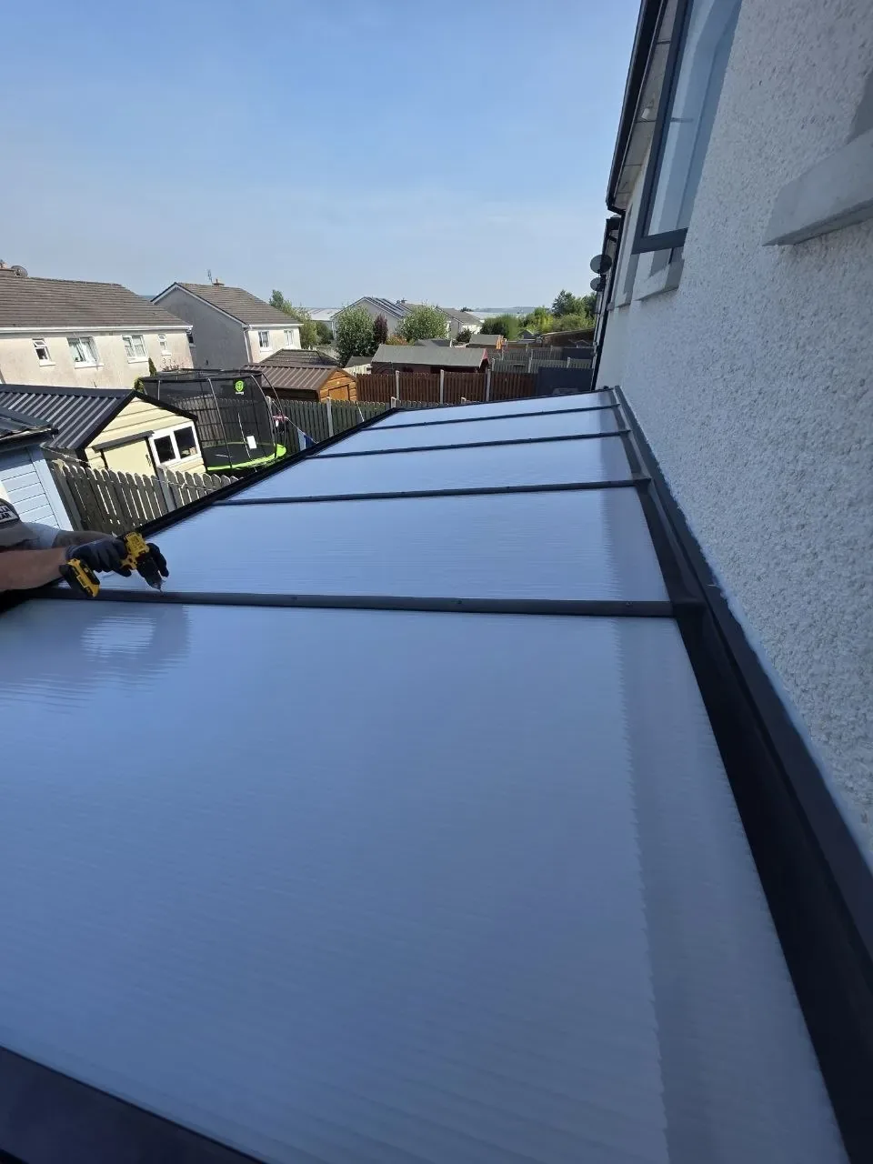 Clear polycarbonate roof panels fitted to the wall-mounted pergola