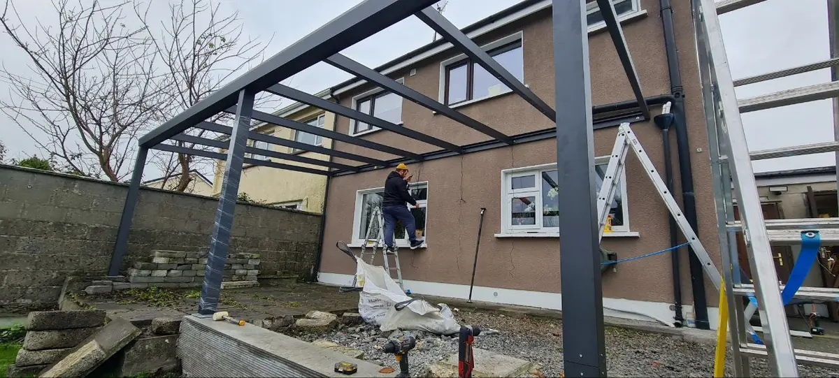Black aluminium pergola frame during installation behind the home in Tuam