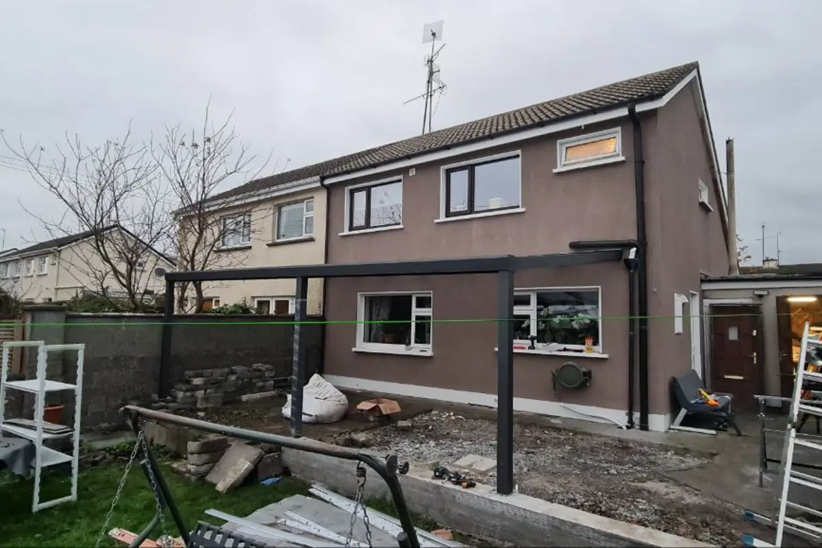 Black wall-mounted aluminium pergola with a polycarbonate roof at a residential property in Tuam, County Galway
