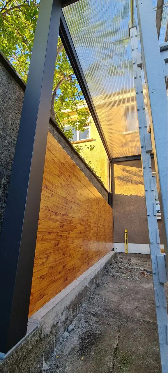 Angled view beneath the polycarbonate roof and wood-effect aluminium side wall in Tuam