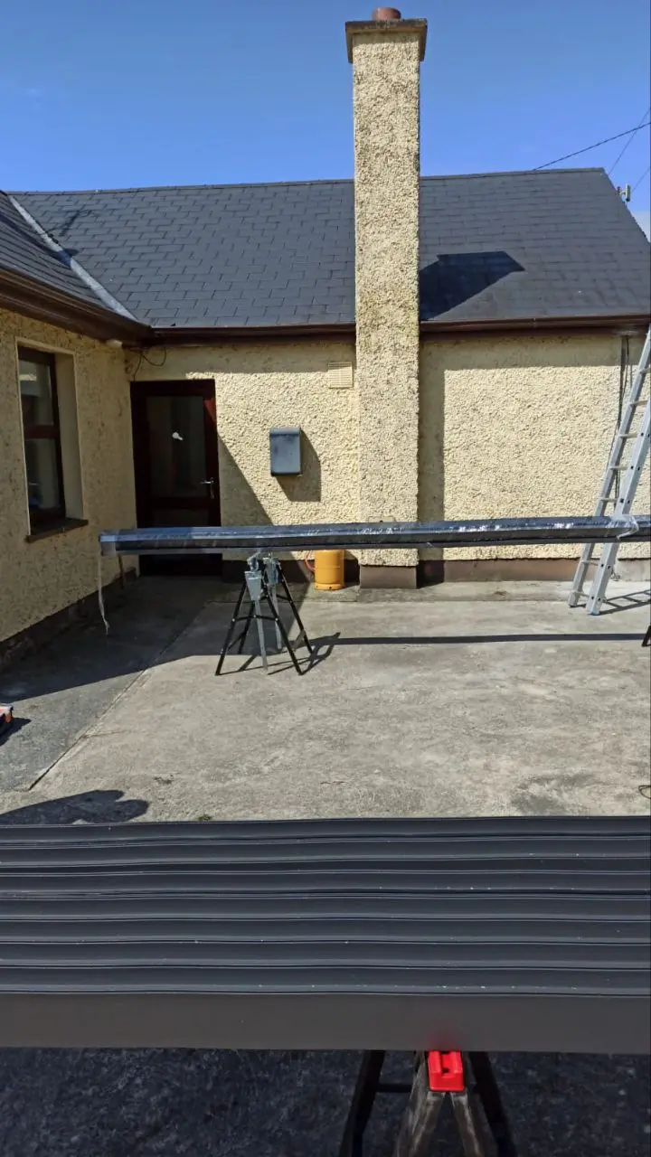 Black aluminium beams prepared during installation of the wall-mounted pergola