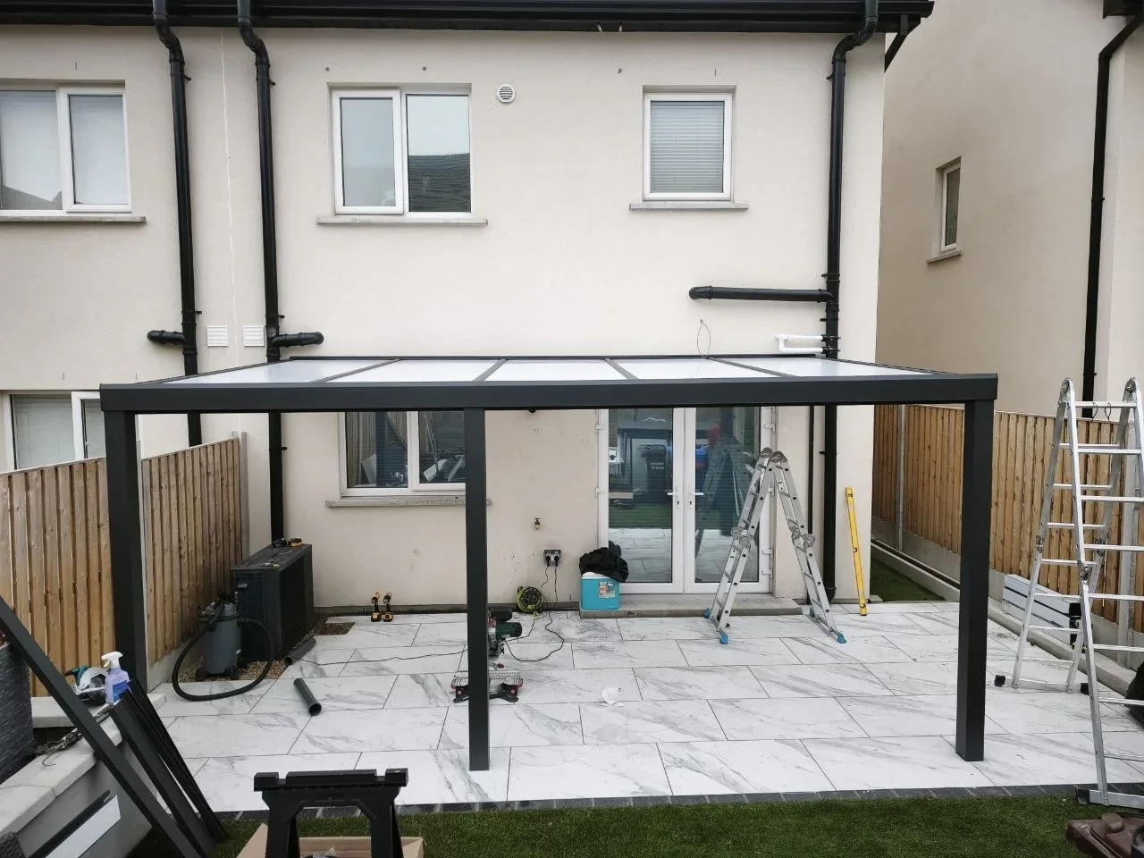 Wall-mounted aluminium pergola during installation over the residential patio in Cork