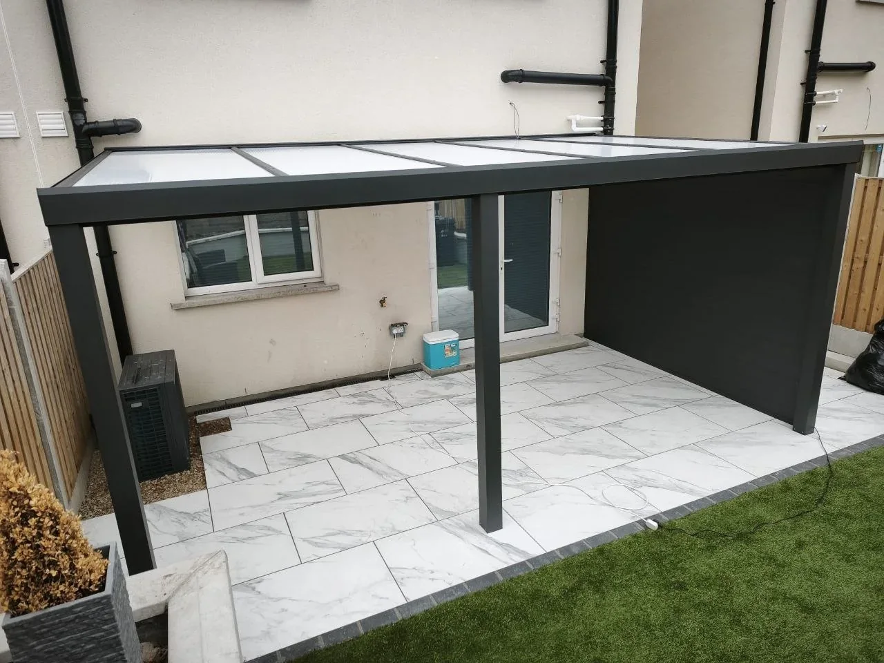 Completed wall-mounted aluminium pergola with milk polycarbonate roof and side wall in Cork