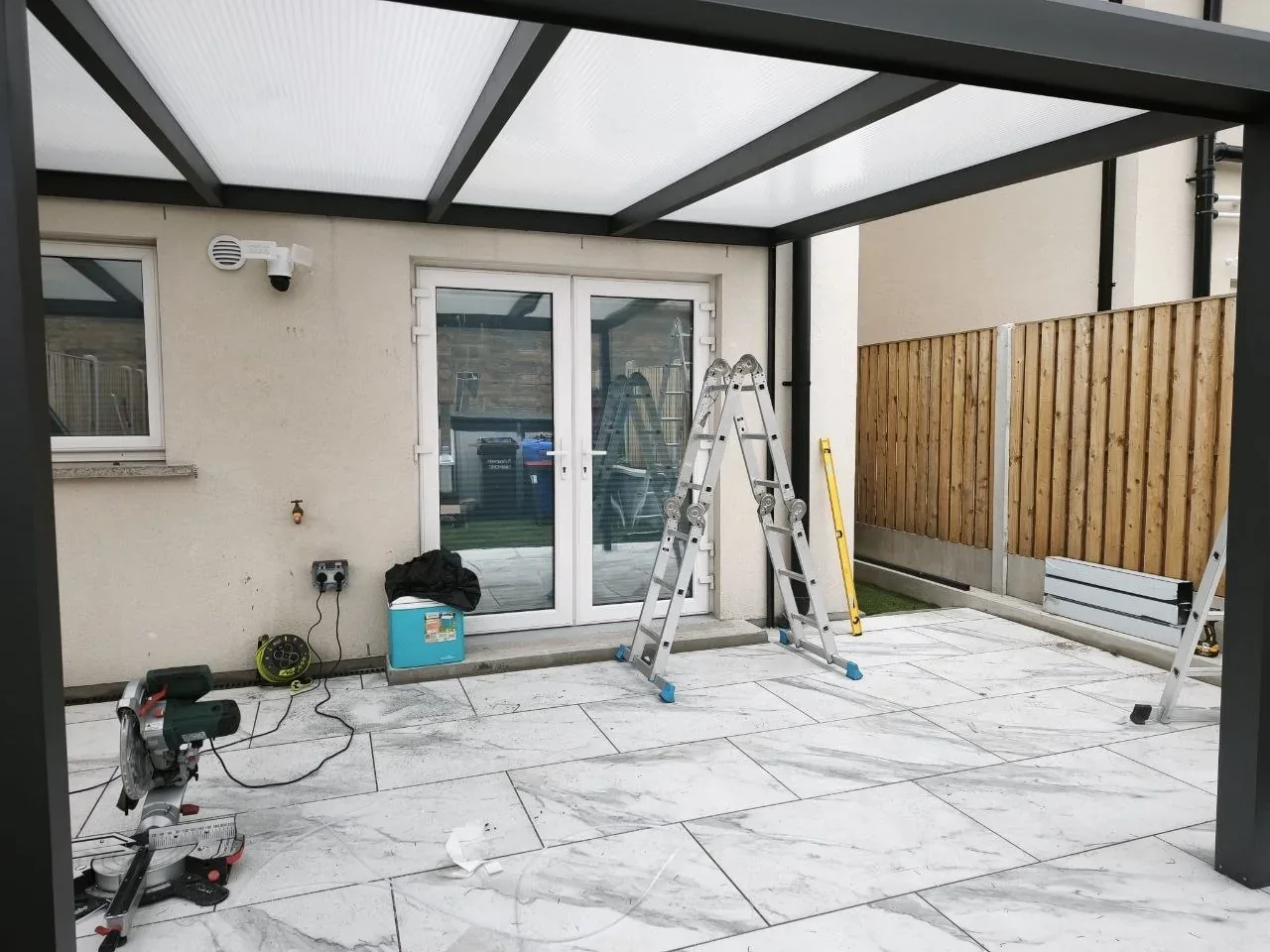 Sheltered patio beneath the milk polycarbonate roof of the Cork pergola